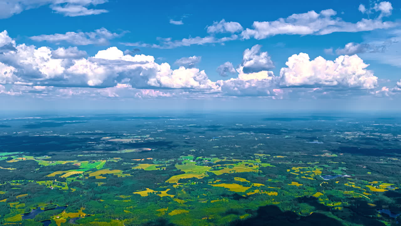 Shadows from clouds crossing rural farms and forests in Europe's fertile, summer landscape - high altitude aerial time lapse