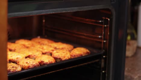 woman's' hands taking out sliced bread with cheese and sausage from oven, close up