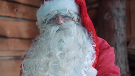 Close-up-of-Santa-Claus,-outside-next-to-a-wooden-house-and-talking-and-shaking-hands