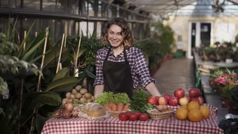 Portrait-Of-Beautiful-Woman-Farmer-Selling-Organic-Food-In-Farm-Market-Smiling-Looking-At-Camera-Standing-Indoors-In-Spacious,-Sunny-Greenhouse