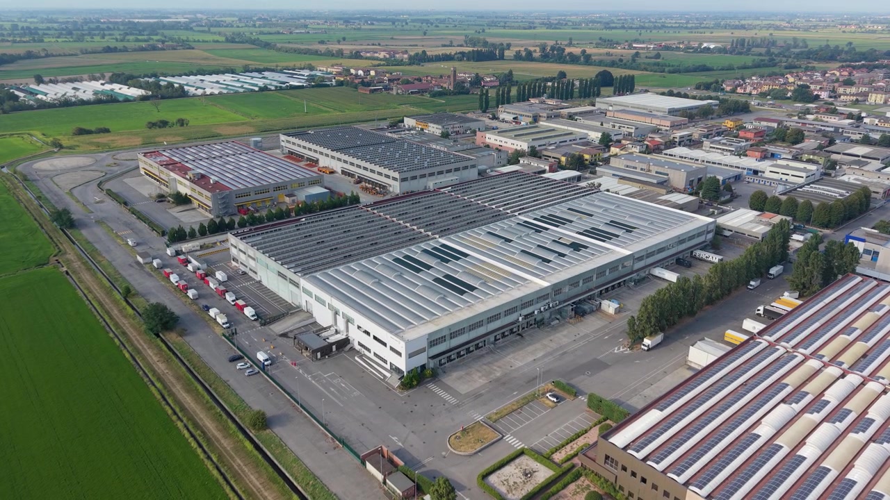 Vista aerea di un'importante struttura logistica in Lombardia, Italia, che mostra l'infrastruttura del magazzino e le operazioni di trasporto. Adatto per progetti multimediali di catena di approvvigionamento, aziendali e industriali