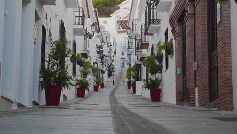 narrow street in spanish town of mijas below mountain, tilt shot