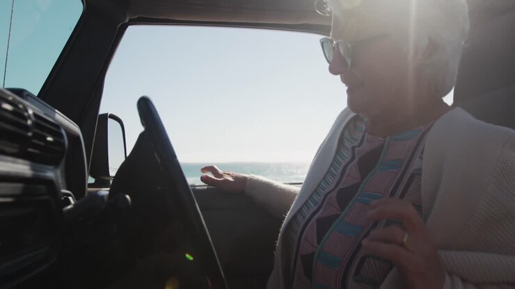 Donna anziana che guida la macchina in spiaggia