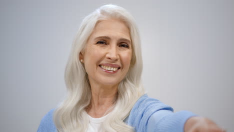 Smiling-elderly-woman-flirting-inside.-Happy-lady-pointing-to-camera-indoors.