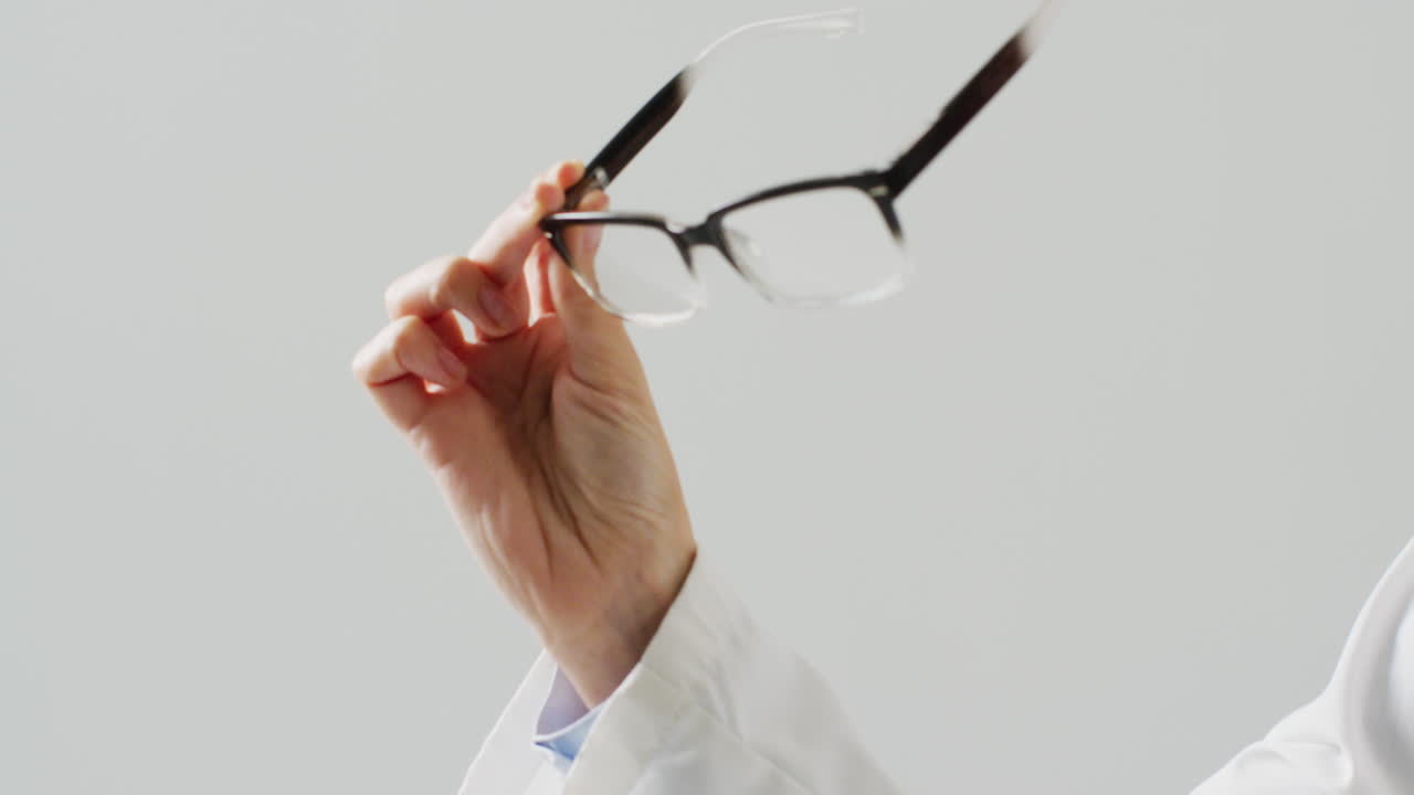 video de la sección media de una doctora caucásica sosteniendo gafas, con espacio para copiar.