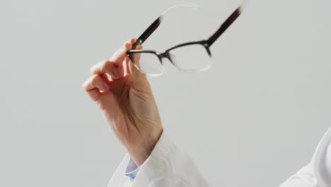 video of midsection of caucasian female doctor holding glasses, with copy space