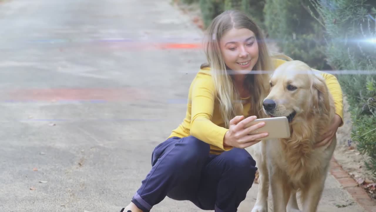 Blue and red light trails against caucasian woman talking a selfie with her dog outdoors