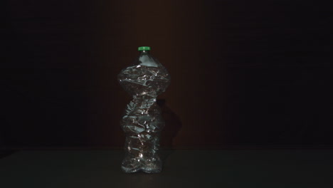 botella de plástico se aplasta, fondo oscuro