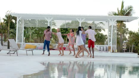 happy diverse group of friends dancing and playing at swimming pool