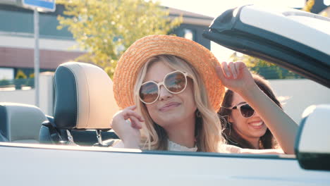 two women friends enjoying a summer road trip in a convertible car