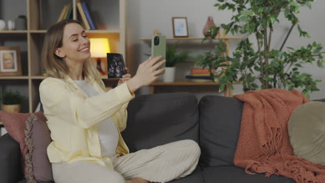 pregnant woman taking a selfie with ultrasound image