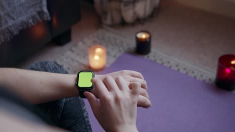 mujer anónima sentada usando un reloj de fitness inteligente de pantalla verde durante el ejercicio