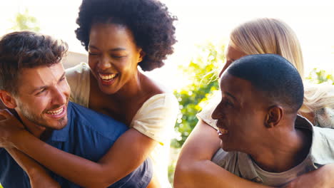portrait of multi-cultural friends on holiday with men giving women piggybacks