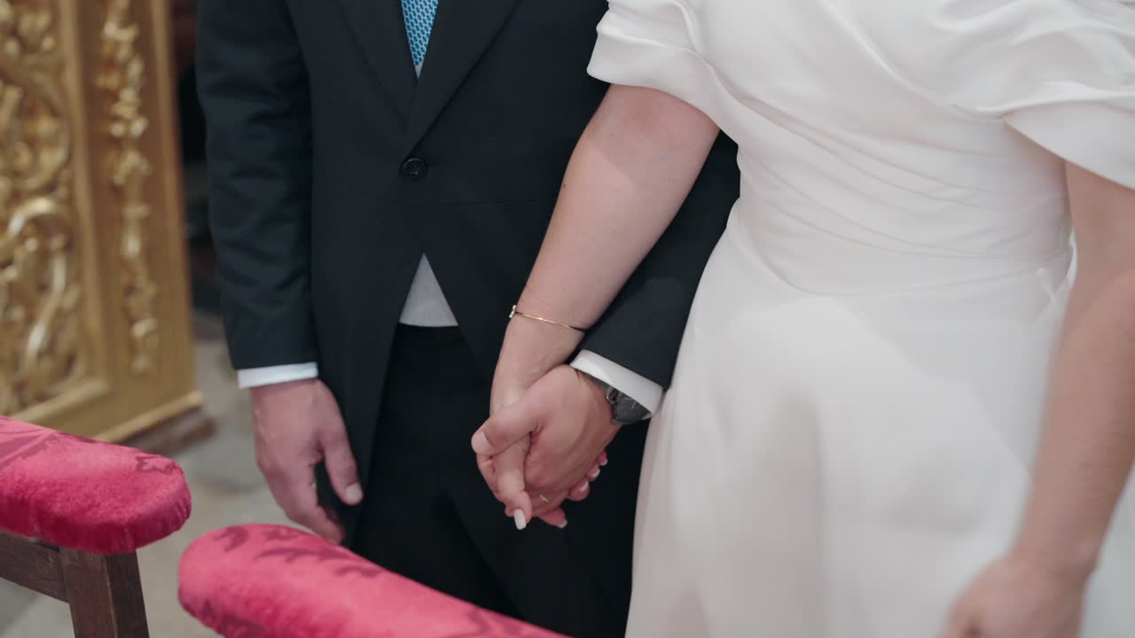 Newlywed couple holding hands during a wedding ceremony inside a church