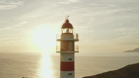 toma cercana de un faro con sol y océano en el fondo a la hora dorada