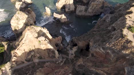 Paseo-Marítimo-Con-Escalones-Empinados-Desde-El-Acantilado-Superior-Que-Conducen-A-Una-Playa-Rocosa-Y-Protegida,-Lagos,-Algarve