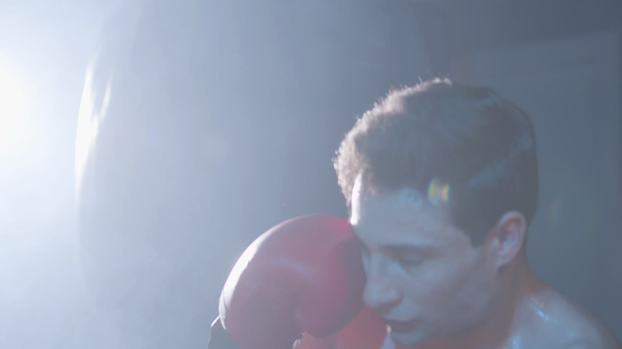 강한 남성 권투 선수 가 운동 할 때 권투 가방 을 때리고 있다