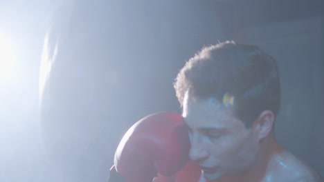 Strong-male-boxer-hitting-punching-bag-while-working-out