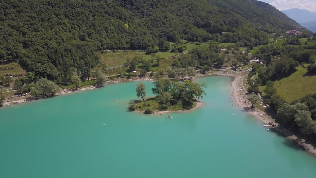 antena ascendente de una pequeña isla en el lago de vacaciones, verano azul turquesa, lago di tenno cerca del pueblo ville del monte