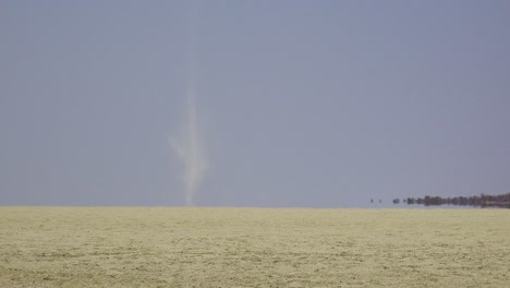 a dust devil blows across the dry and desolate etosha pan in namibia