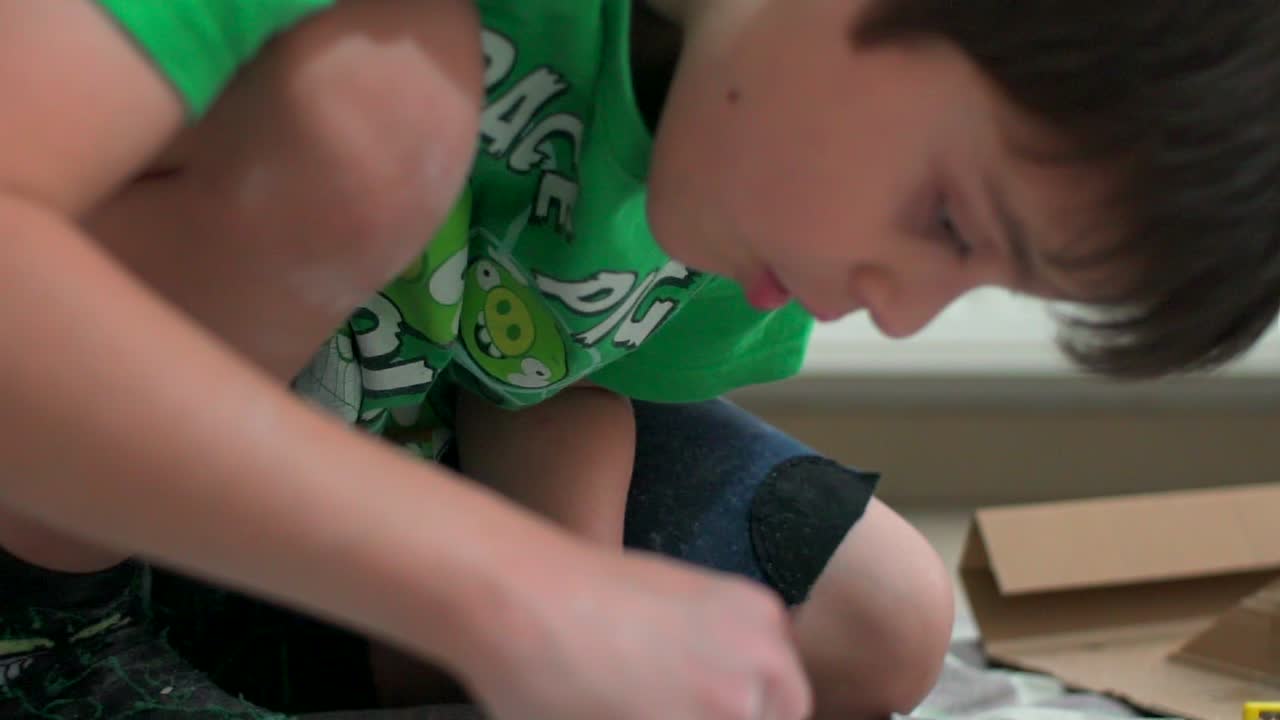 A child engaged in a dig kit activity, carefully excavating a hidden object from a plaster block.
