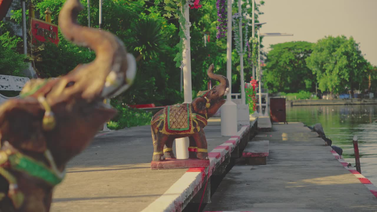 A Riverside Walkway Adorned With Decorative Elephant Statues, Vibrant Flowers, and Lush Greenery in Bangkok, Thailand - Static Shot