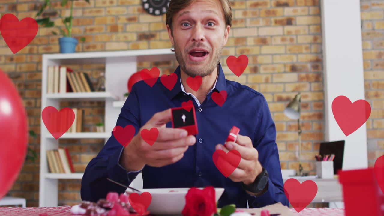 animación de iconos de corazón rojo sobre hombre caucásico sosteniendo anillo de compromiso