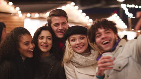 Jóvenes-Amigos-Posando-Para-Selfie-En-El-Mercado-De-Navidad