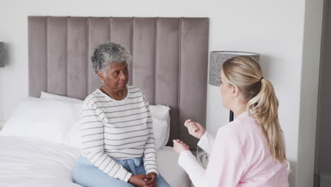 Caucasian-female-nurse-talking-to-senior-african-american-woman,-copy-space,-slow-motion