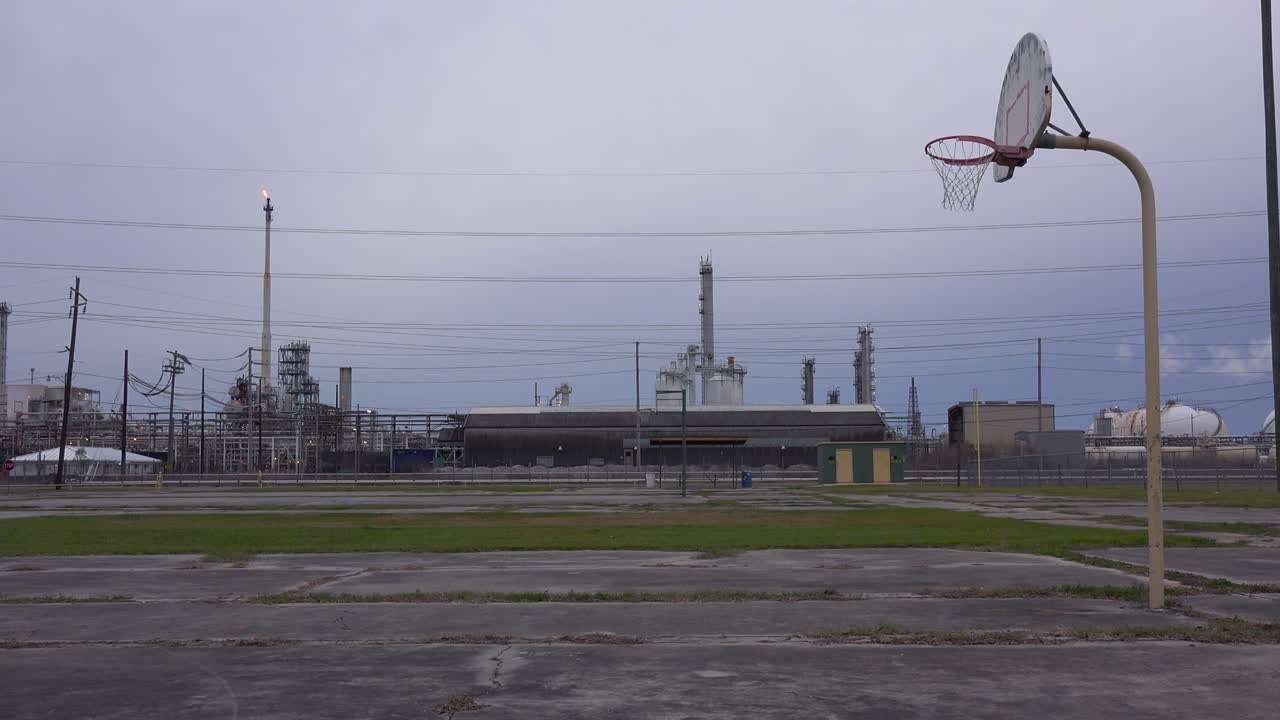 una cancha de baloncesto vacía se encuentra frente a una gran refinería de petróleo 1