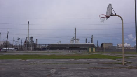 Una-Cancha-De-Baloncesto-Vacía-Se-Encuentra-Frente-A-Una-Gran-Refinería-De-Petróleo-1