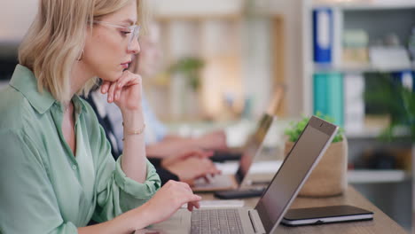 mujer concentrada trabajando en una computadora portátil en la oficina