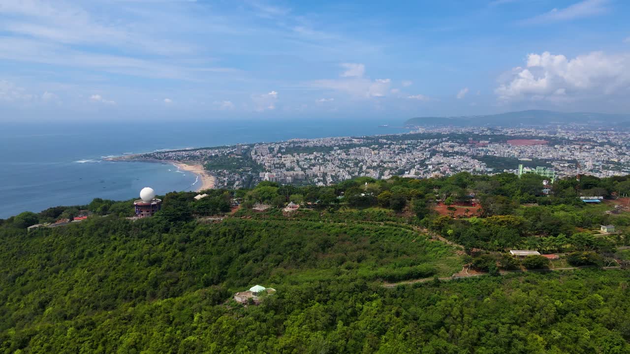 Aerial drone shot of Vizag city, capturing its vibrant infrastructure and lush green hills in the background.