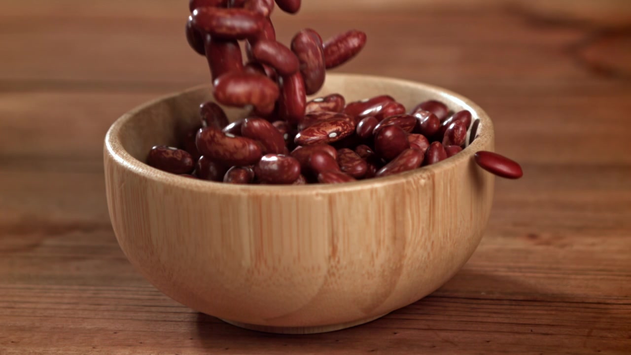 Red Kidney Beans Falling into a Wooden Bowl in Slow Motion