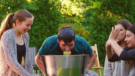 Freunde-Beobachten,-Wie-Ein-Teenager-Auf-Einer-Gartenparty-Einen-Apfel-Hüpft