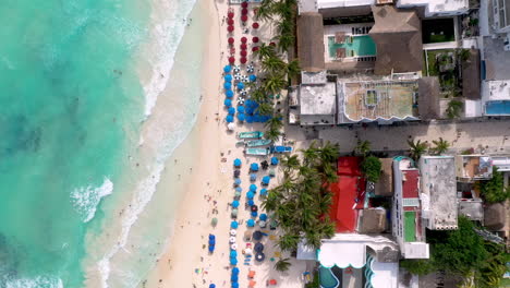 Disparo-Cinematográfico-De-Drones-Descendentes-Que-Descienden-Hacia-La-Gente-En-La-Playa-De-Playa-Del-Carmen,-México,-Agua-Azul-Clara-Del-Océano