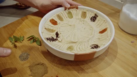 Decorating-hummus-dish-with-cumin,-paprika,-rosemary-spices-by-hand