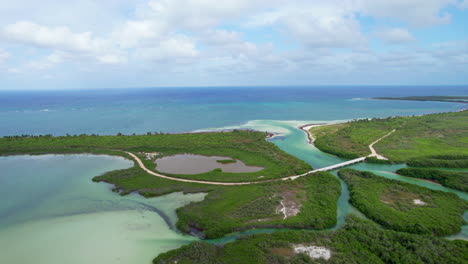 drone-fly-above-Tulum-Mexico-Sian-Kaʼan-Reserve-a-biosphere-with-Mexican-Caribbean-Sea,-off-road-narrowed-path-connecting-the-peninsula-for-guided-tour-visiting-exploring-the-gate-of-heaven