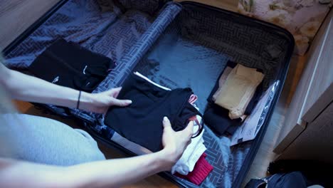 close up of a lady putting her clothes in a suitcase, ready to travel