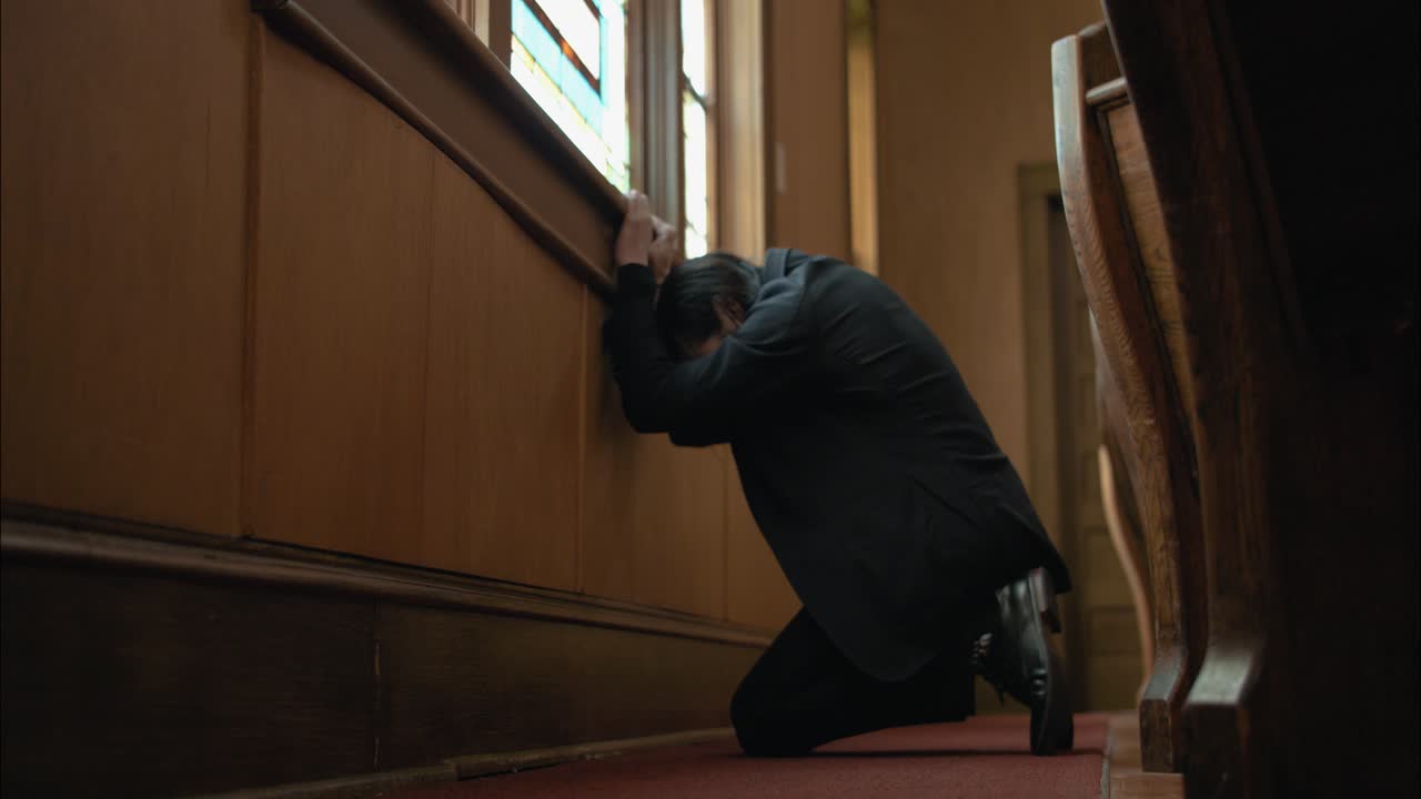A Christian man praying and kneeling inside old church building