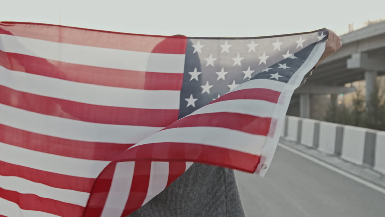 Donna che tiene in mano una bandiera americana su un'autostrada