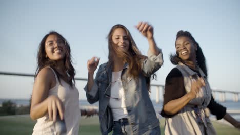 smiling young women dancing together in park