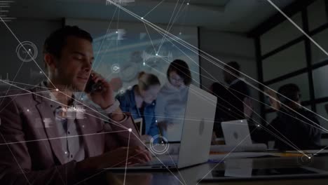 red de conexiones a través de empresario caucásico hablando en teléfono inteligente y usando portátil en la oficina
