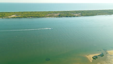 aerial view of one motorboat moving on piedras river along spit, spain, marina el rompido daytime