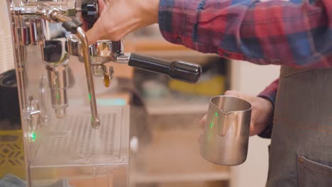 barista preparing steamed milk for cappuccino, checking temperature with hand