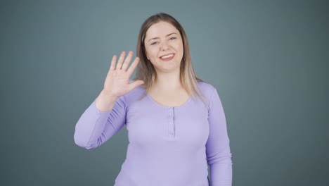 Happy-young-woman-waving-at-camera.