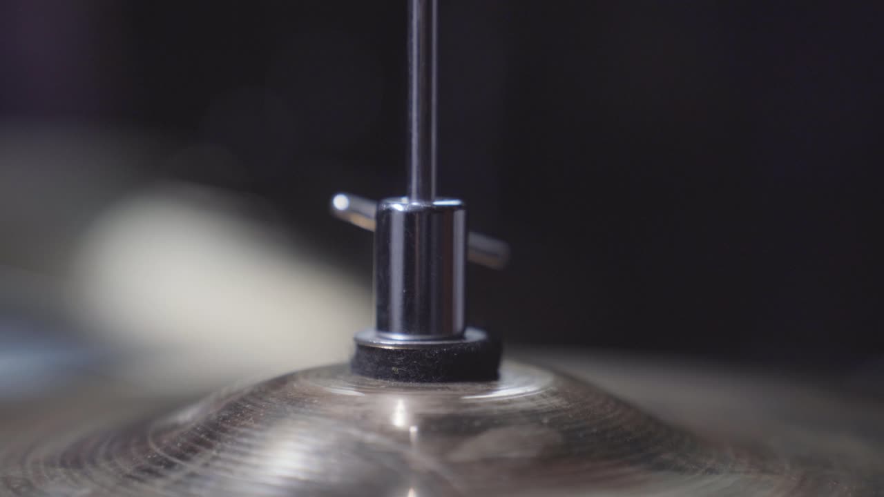 Person adjusting height screw on drum set's hi-hat cymbal