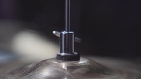 Person adjusting height screw on drum set&#039;s hi-hat cymbal