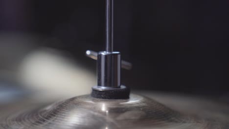 person adjusting height screw on drum set's hi-hat cymbal