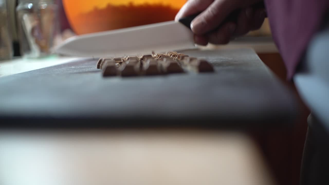 Close up on woman's hands chopping chocolate , preparing homemade energy bars